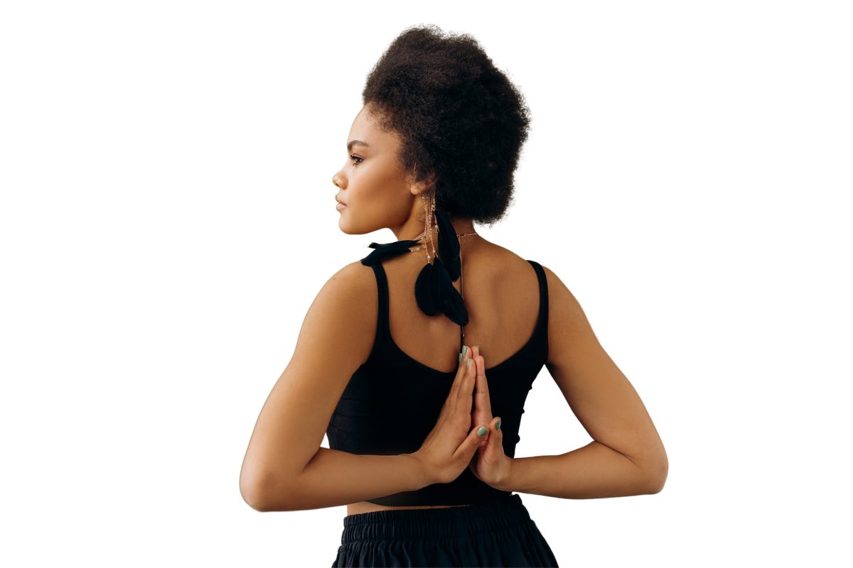 Black woman in a calm yoga pose with hands together behind her back.